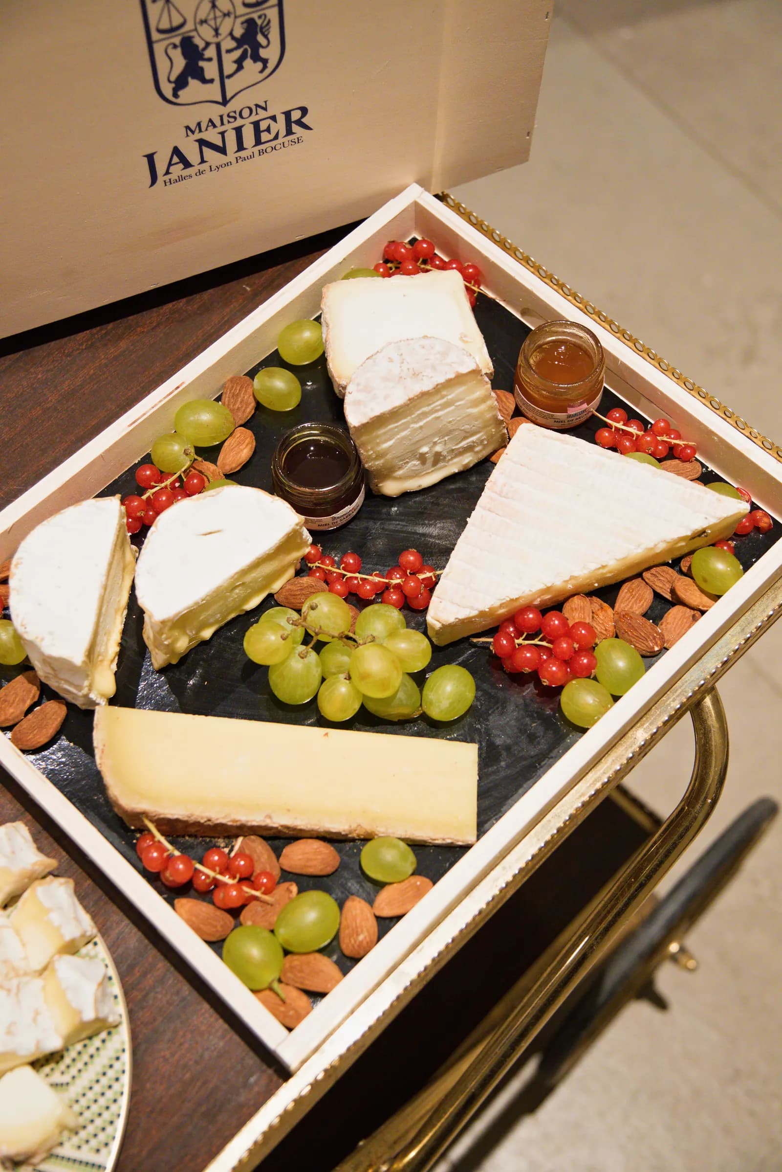 Plateau de fromages affinés Maison Janier vu de dessus, raisin, groseilles et miel