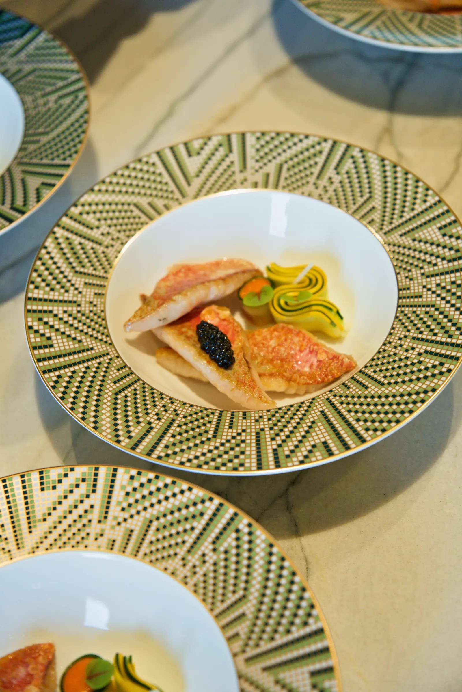 Filets de rouget dorés surmontés de caviar, accompagnés d'un ruban de courgette bicolore
