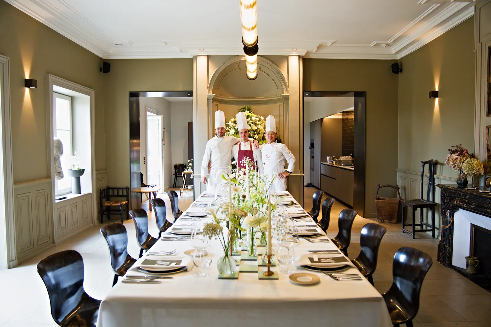 Grande table dressée avec fleurs, chandelles et verrerie dans la salle à manger du château