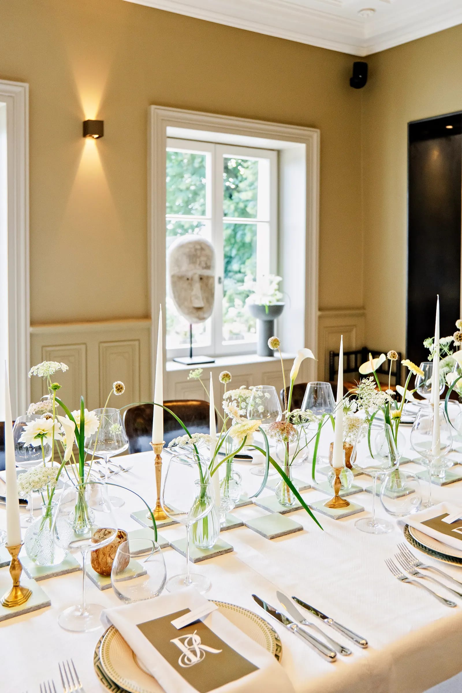 Table dressée élégante avec bougies fines et fleurs blanches en soliflores