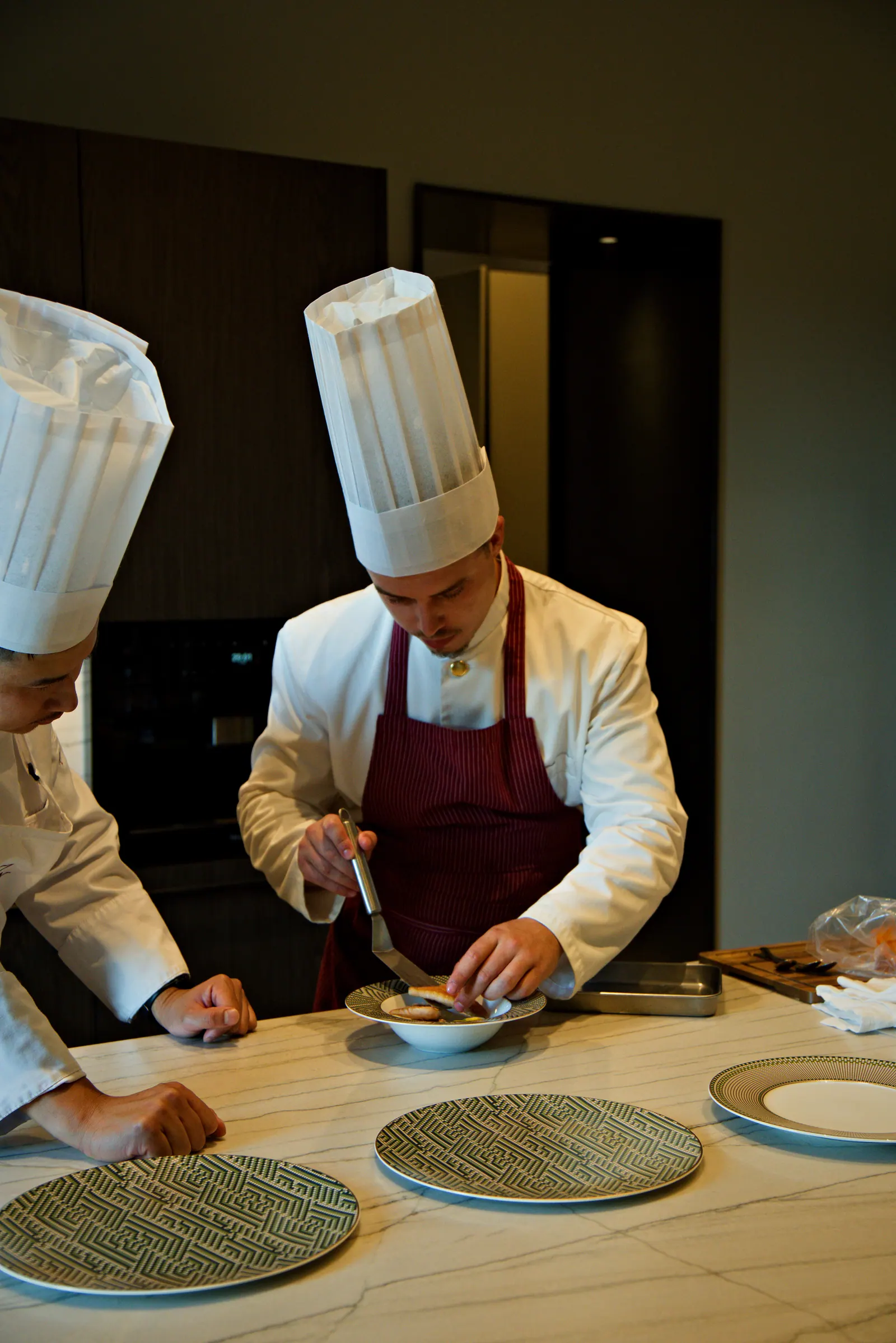 Chef Sean in a burgundy apron plating a dish during service