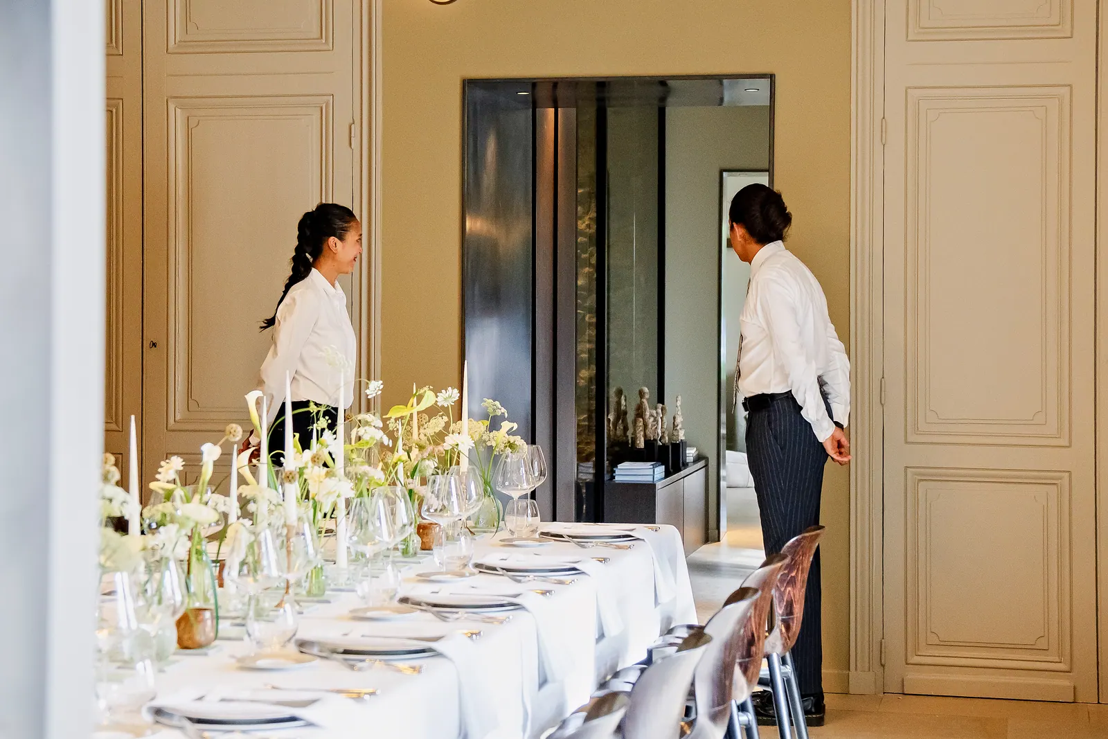Long table set with white flowers, candles and fine glassware in a château salon, for a private event