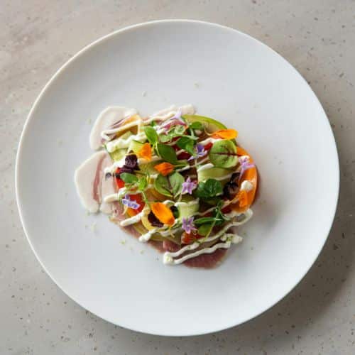 Artistic salad with crunchy vegetables, edible flowers, and light cream – private chef plating in Lyon.