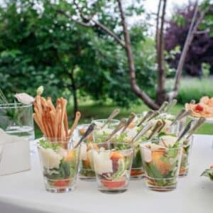 Verrines apéritives fraîches avec légumes croquants, parmesan et gressins pour cocktail gastronomique en plein air.