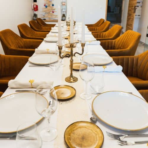 Table élégante dressée pour un dîner gastronomique privé avec vaisselle raffinée, chandeliers et chaises confortables.