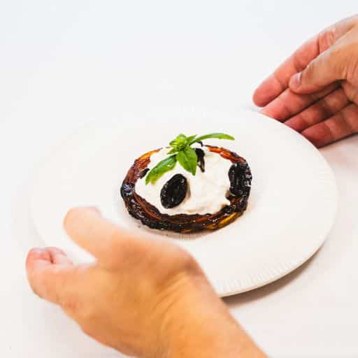 Tarte façon tatin de tomate, stracciatella fumée, olive noire et basilic, nappée de vinaigre balsamique