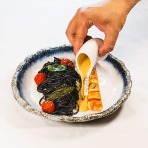 Gambas grillée avec pâtes à l'encre de seiche, tomates cerises sautées, basilic et sauce crustacés réalisée avec les carcasses.